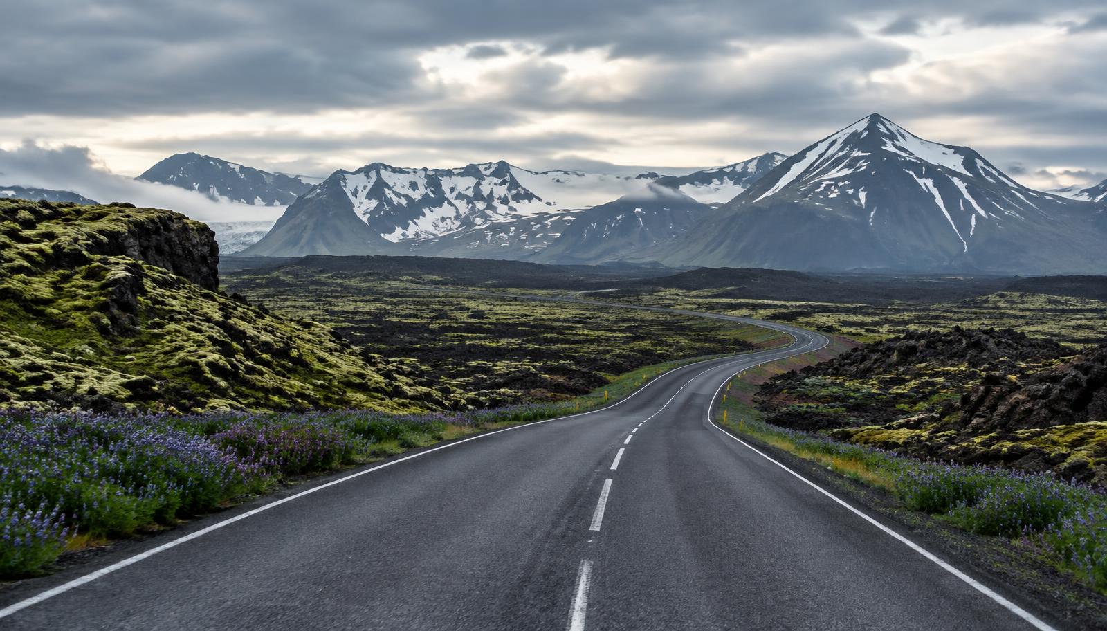 Carretera islandesa entre campos de lava y montañas nevadas