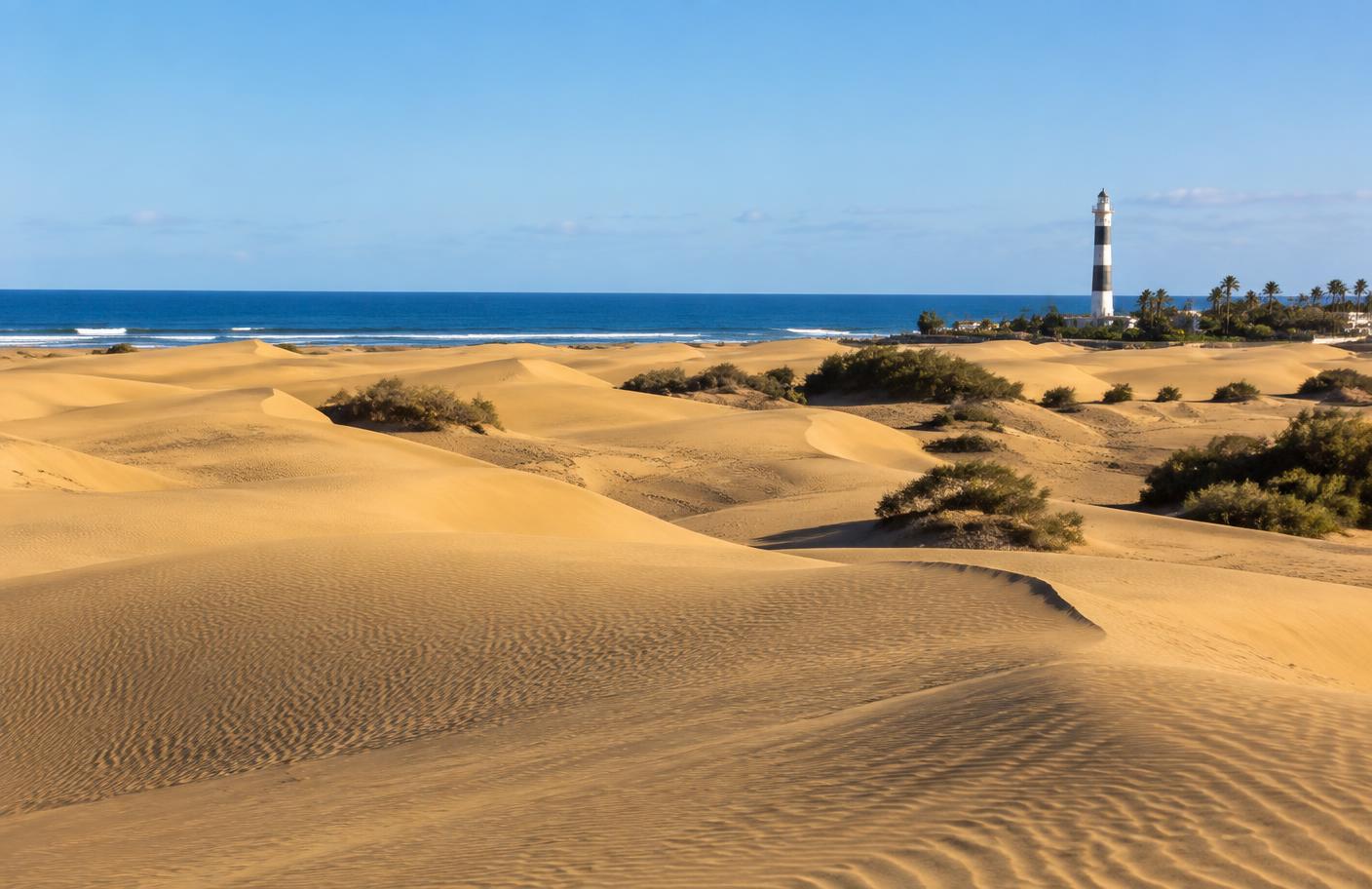 Dunas doradas de Maspalomas con el faro junto al océano en Gran Canaria